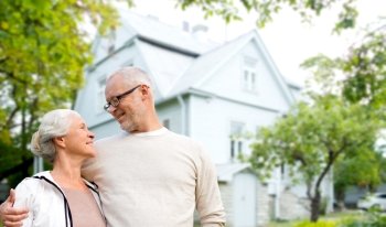 family, age, home, real estate and people concept - happy senior couple hugging over living house background