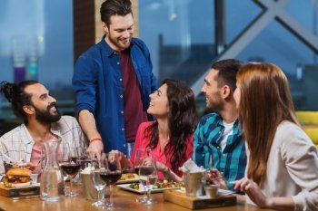 leisure, eating, food and drinks, people and holidays concept - smiling friends having dinner and drinking red wine at restaurant