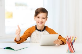 leisure, children, technology, education and people concept - smiling boy with tablet pc computer and notebook showing thumbs up at home