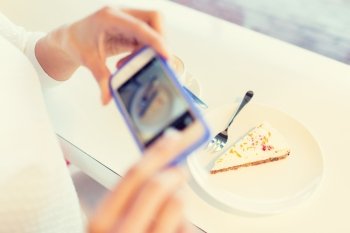 food, people, technology and lifestyle concept - close up of woman hands with smartphone taking cake picture at cafe