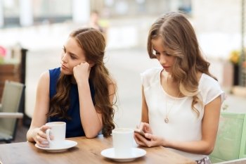 technology, internet addiction, lifestyle, friendship and people concept - young women or teenage girls with smartphones and coffee cups at cafe outdoors