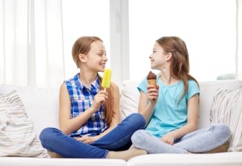 people, children, friends and friendship concept - happy little girls eating ice-cream at home