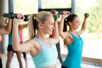 fitness, sport, training and lifestyle concept - group of women with dumbbells in gym