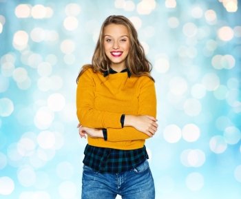 people, style and fashion concept - happy young woman or teen girl in casual clothes over blue holidays lights background