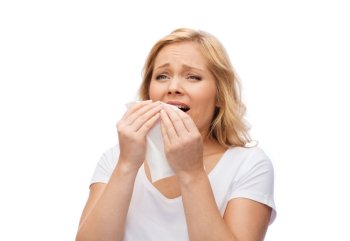 people, healthcare, rhinitis, cold and allergy concept - unhappy woman with paper napkin sneezing