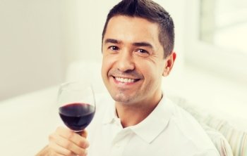 profession, drinks, leisure, holidays and people concept - happy man drinking red wine from glass at home
