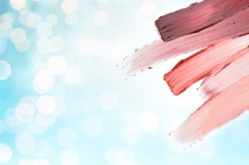 cosmetics, makeup, holidays and beauty concept - close up of lipstick smear sample over blue lights background