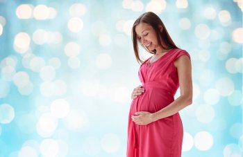 pregnancy, motherhood, people and expectation concept - happy pregnant woman with big tummy over blue holidays lights background