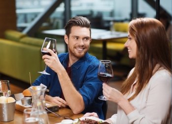 leisure, eating, food and drinks, people and holidays concept - smiling couple having dinner and drinking red wine at restaurant