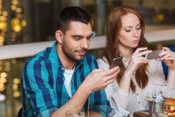 leisure, technology, lifestyle and people concept - couple with smartphones dining at restaurant