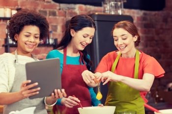 cooking class, friendship, food, technology and people concept - happy women with tablet pc in kitchen