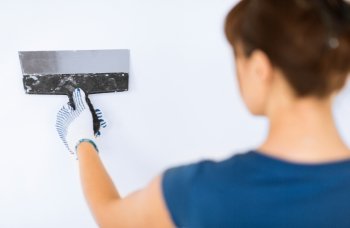 interior design and home renovation concept - woman plastering the wall with trowel. woman plastering the wall with trowel