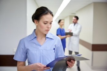 clinic, profession, people, health care and medicine concept - female doctor or nurse with clipboard at hospital
