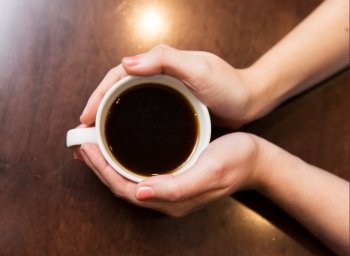 drinks, people and lifestyle concept - close up of woman hands holding cup with hot black coffee