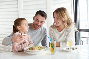 family, parenthood, food and people concept - happy mother, father and little girl eating pasta for dinner at restaurant or cafe