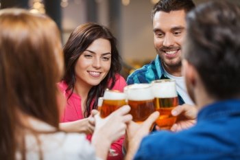 leisure, drinks, celebration, people and holidays concept - smiling friends drinking beer and clinking glasses at restaurant or pub