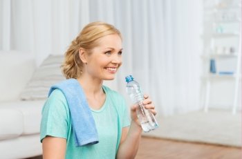 fitness, sport, people and healthy lifestyle concept - happy woman with bottle of water drinking after exercising at home
