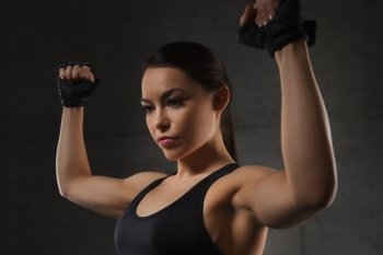sport, fitness, bodybuilding, weightlifting and people concept - young woman flexing muscles in gym