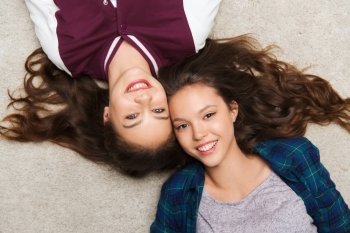 people, friends, teens and friendship concept - happy smiling pretty teenage girls lying on floor