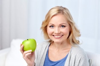 healthy eating, organic food, fruits, diet and people concept - happy middle aged woman with green apple at home