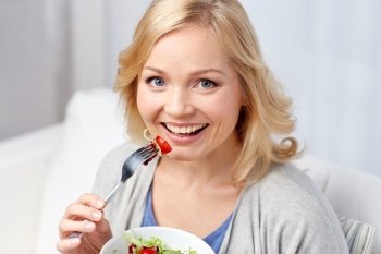 healthy eating, dieting and people concept - smiling young woman eating vegetable salad at home