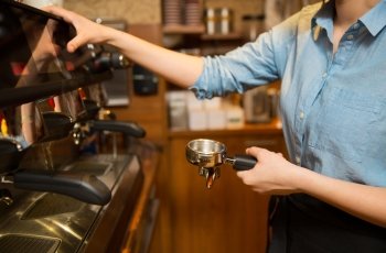 equipment, coffee shop, people and technology concept - close up of woman making coffee by machine at cafe bar or restaurant kitchen