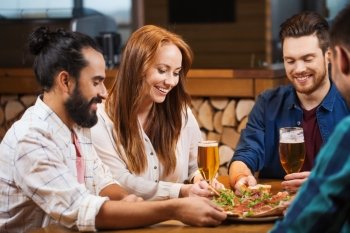 leisure, food and drinks, people and holidays concept - smiling friends eating pizza and drinking beer at restaurant or pizzeria
