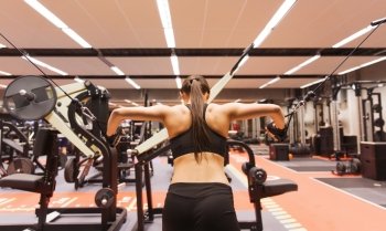 sport, fitness, bodybuilding, lifestyle and people concept - woman flexing muscles on cable machine in gym