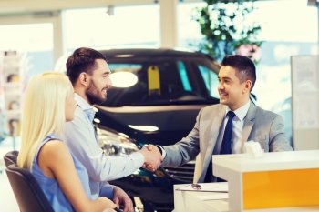 auto business, car sale, and people concept - happy couple with dealer shaking hands in auto show or salon
