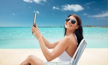 summer vacation, tourism, travel, holidays and people concept - smiling young woman with tablet pc computer sunbathing in lounge or folding chair over tropical beach background