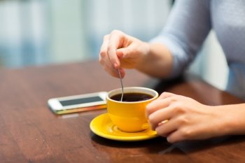 drinks, people, technology and lifestyle concept - close up of young woman with smartphone drinking coffee at cafe