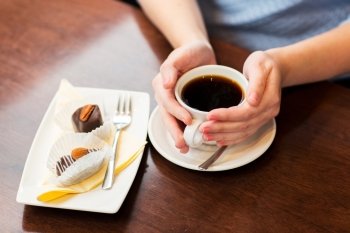drinks, people and lifestyle concept - close up of woman hands holding cup with hot black coffee and dessert