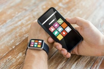 modern technology, application and people concept - close up of male hand holding smart phone and wearing watch with app icons on screen at home