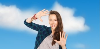 people and teens concept - happy smiling pretty teenage girl showing hands over blue sky and clouds background. happy smiling pretty teenage girl showing hands