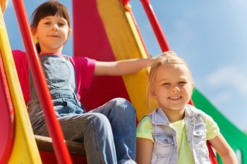 summer, childhood, leisure, friendship and people concept - happy kids on children playground climbing frame