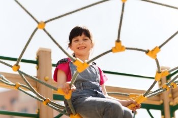 summer, childhood, leisure and people concept - happy little girl on children playground climbing frame