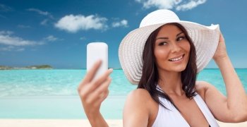 travel, summer, technology and people concept - sexy young woman taking selfie with smartphone over tropical beach background