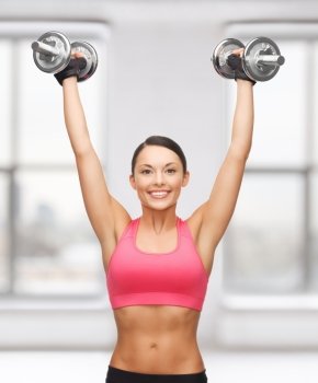 picture of young sporty woman with heavy steel dumbbells