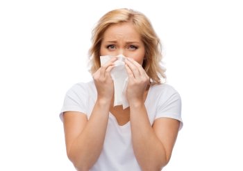 people, healthcare, rhinitis, cold and allergy concept - unhappy woman with paper napkin blowing nose