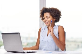 education, business and technology concept - happy african american businesswoman or student with laptop computer and papers at office