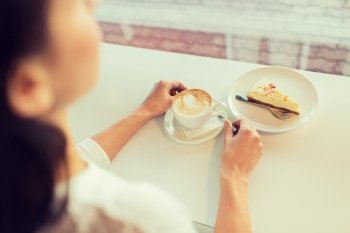 leisure, food and drinks, people and lifestyle concept - close up of young woman hands eating cake and drinking coffee at cafe