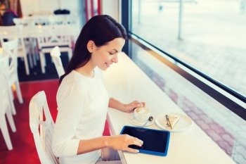 leisure, drinks, people, technology and lifestyle concept - smiling young woman with tablet pc computer drinking coffee at cafe