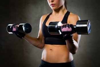 sport, fitness, bodybuilding, weightlifting and people concept - close up of woman flexing arms with dumbbell in gym