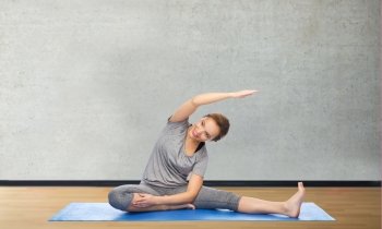 fitness, sport, people and healthy lifestyle concept - happy woman making yoga and stretching on mat over gym room background