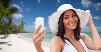 travel, summer, technology and people concept - sexy young woman taking selfie with smartphone over tropical beach with palms background