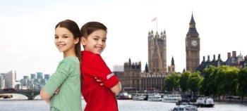 childhood, travel, tourism and people concept - happy smiling boy and girl standing back to back over london city background