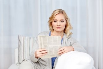 news, press, media, leisure and people concept - woman reading newspaper at home