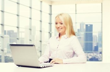 education, business and technology concept - smiling businesswoman with laptop computer over office room with city view window background