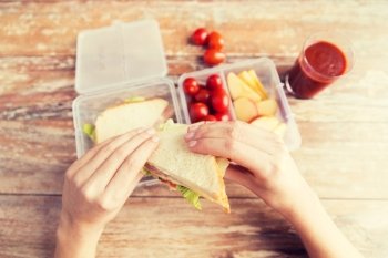 healthy eating, storage, dieting and people concept - close up of woman hands with food in plastic container at home kitchen