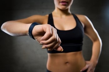 sport, fitness, technology and people concept - close up of young woman with heart-rate watch in gym